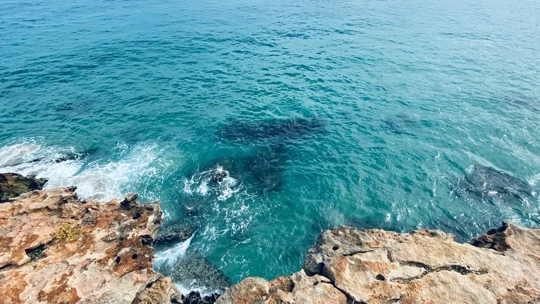 Clear turquoise water below the cliffs at Baía das Pipas