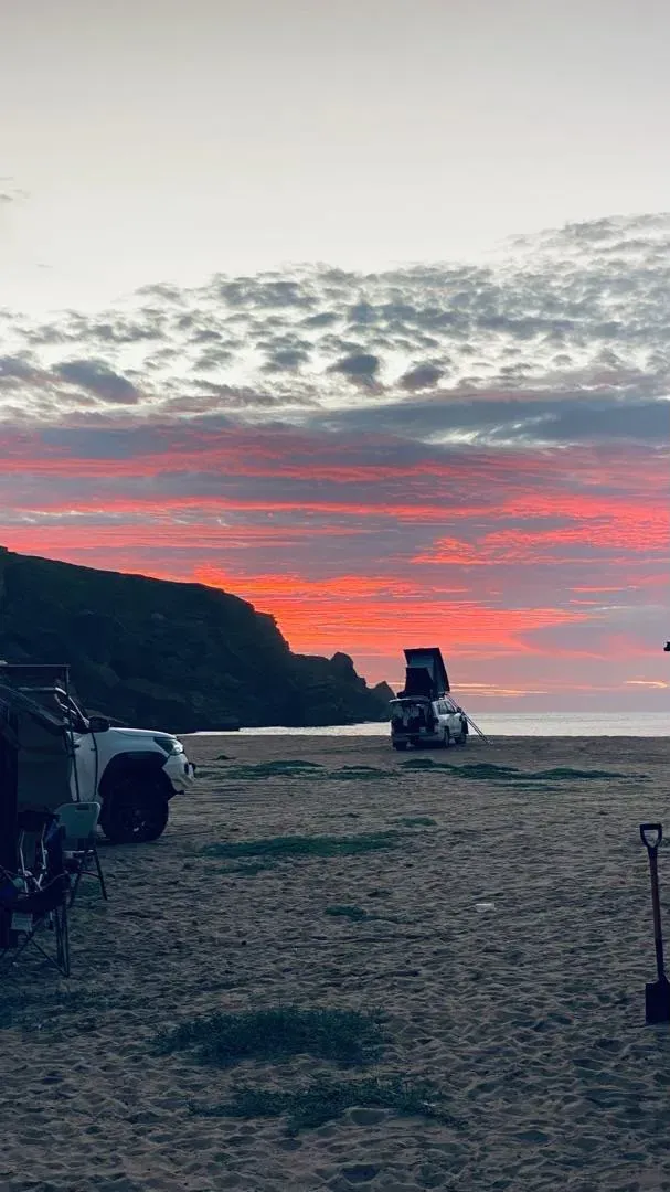 Rooftop tents on the sand as the Baía das Pipas sky turns to fire