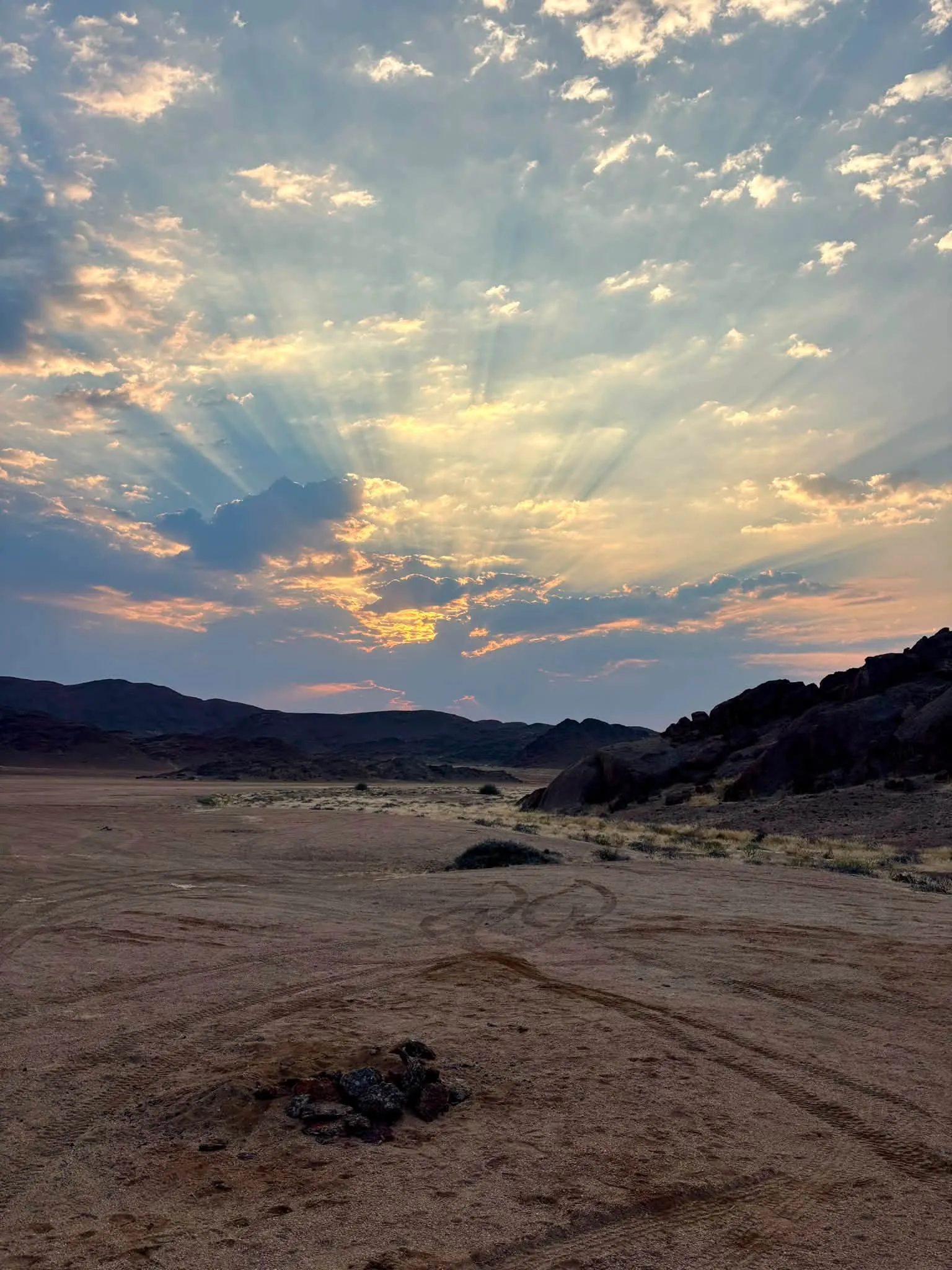 Sun rays over a wild camp on an open gravel plain