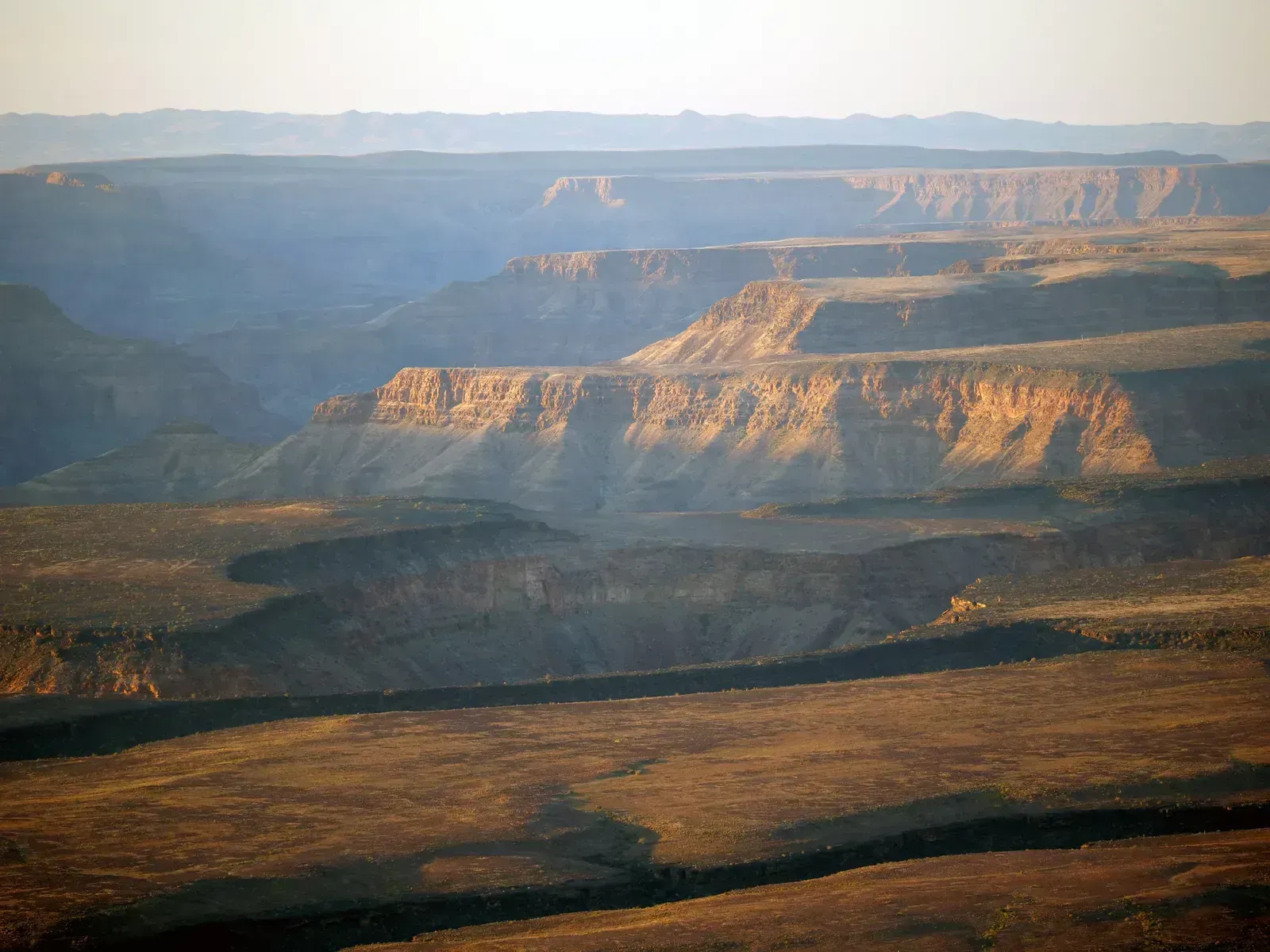 Layered mesas and side ravines fade into the afternoon haze
