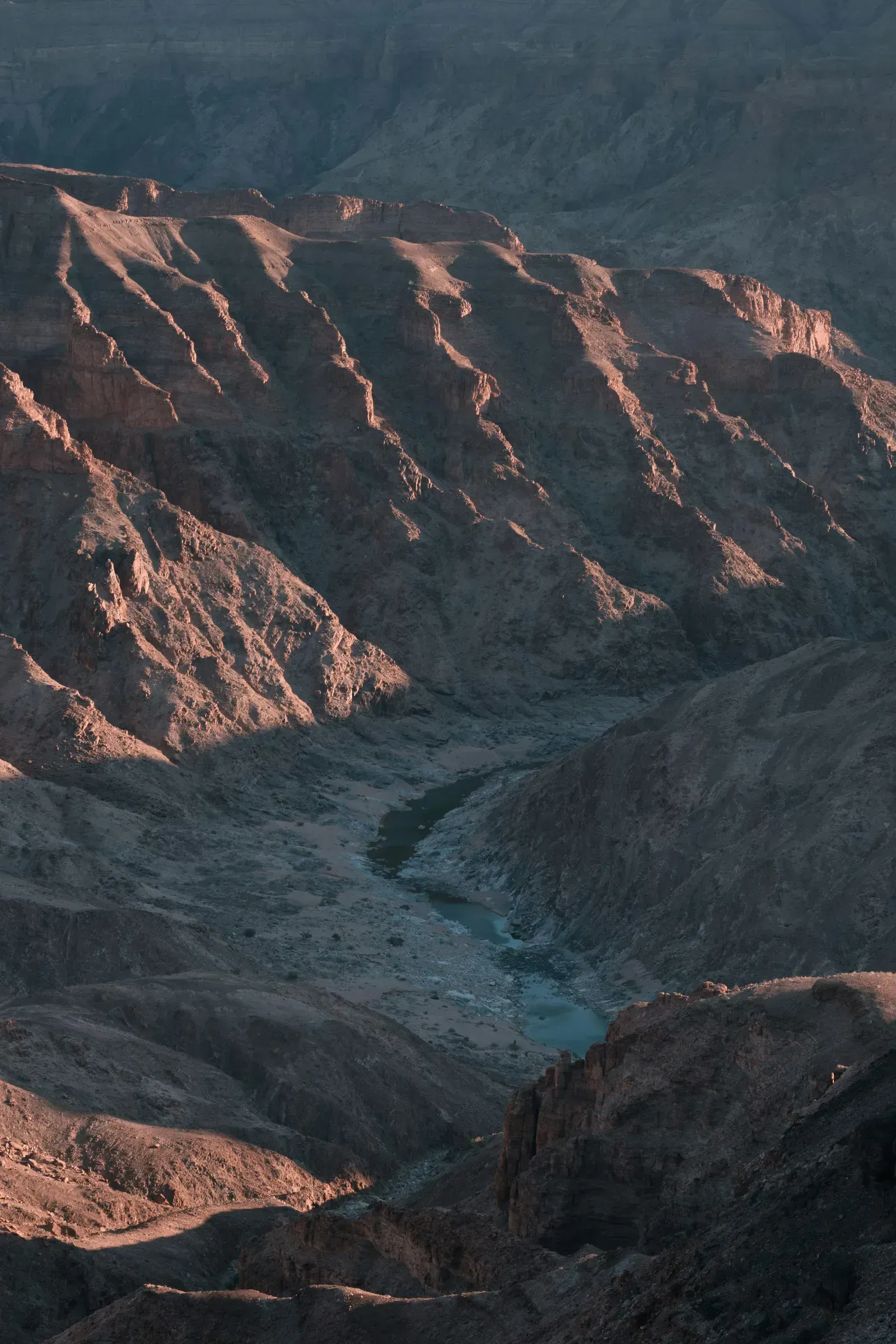 Still river pools catch the last light far below the rim